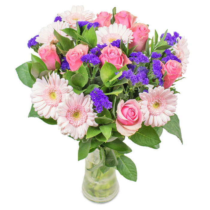 A sophisticated blend of soft pink roses and pale gerbera daisies, arranged by an expert florist from the Manor House locality and presented in a gleaming clear glass vase against a crisp, white backdrop. Approximately eight velvety pink roses make up the heart of the bouquet, some with petals just loosening from tight buds, others blooming into their classic spiral shapes, evoking a sense of timeless romance. Around them, five to seven pale pink gerbera daisies radiate, their broad, rounded heads and creamy centers providing a harmonious counterpoint. Among these are clusters of vivid purple statice, their fine papery blooms lending texture and rich color contrast that echoes the creative diversity of the area. Deep, glossy green foliage envelops the base, echoing the lushness of local parks and providing an invigorating, fresh scent. The clear vase reveals a tangle of healthy stems, the water sparkling in soft daylight, reinforcing the bouquet's freshly delivered vibrancy. Ideal for celebrating birthdays, anniversaries, or simply bringing the serene charm of Manor House indoors, this floral arrangement offers a heartfelt gesture of joy and affection-perfect for homes, offices, and moments of celebration around Seven Sisters Road.